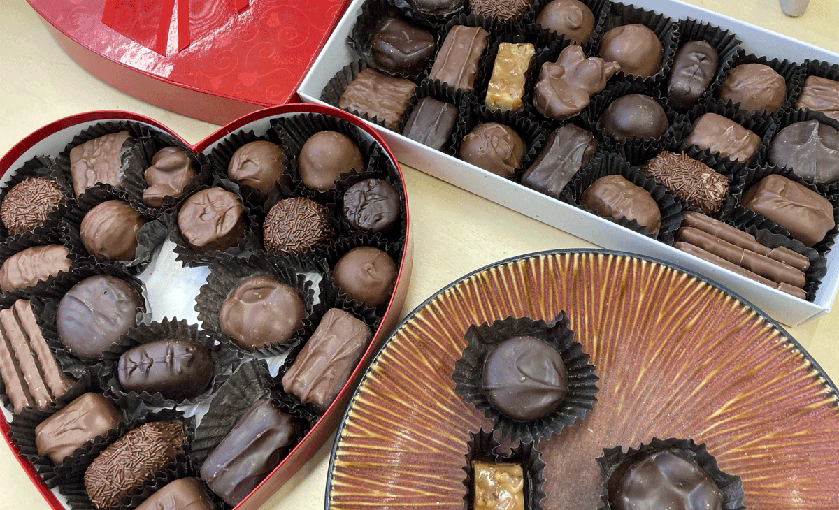 Top-down view of boxes of chocolates and a plate with some chocolates set aside.